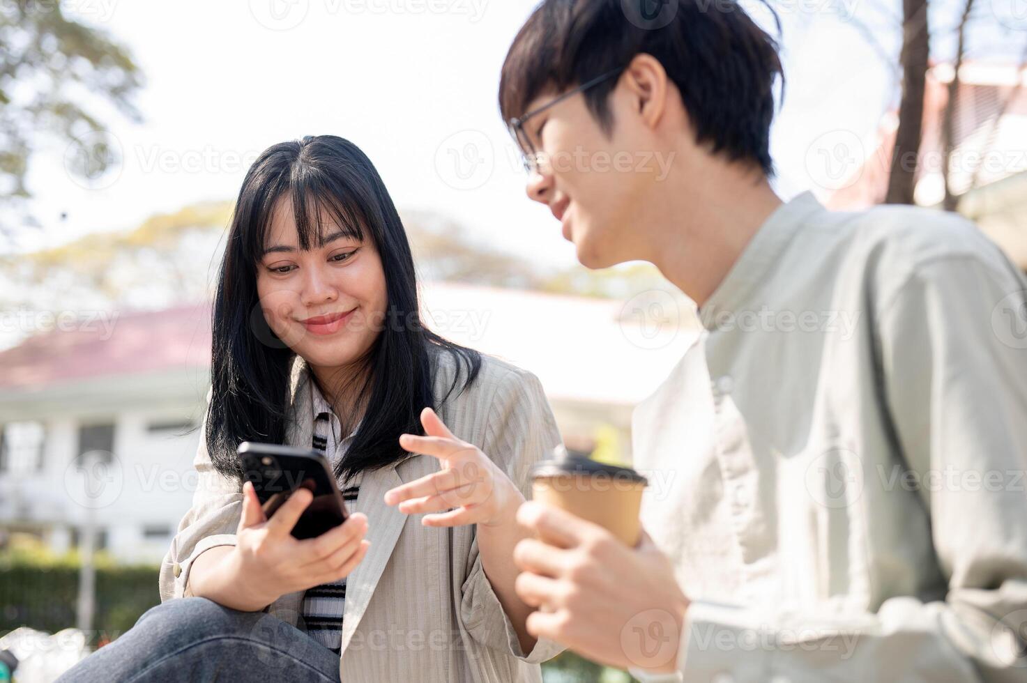 A positive Asian female is enjoying talking with her friend in a city park during her lunch break. photo