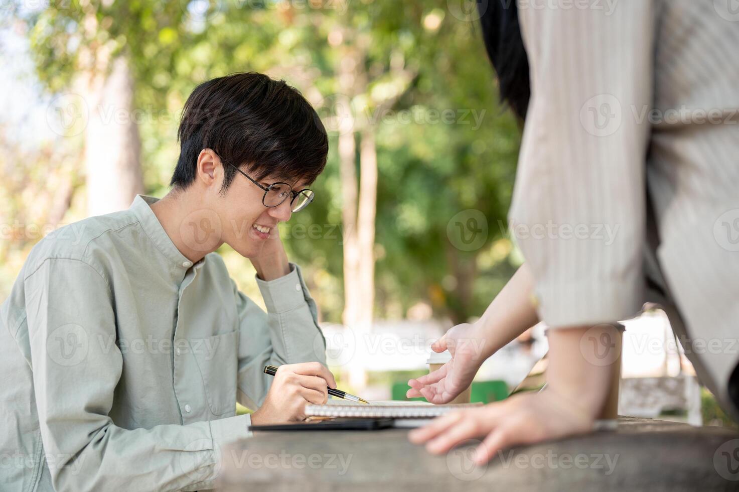A smart Asian male student is sharing his ideas with his friend while collaborating on work together photo
