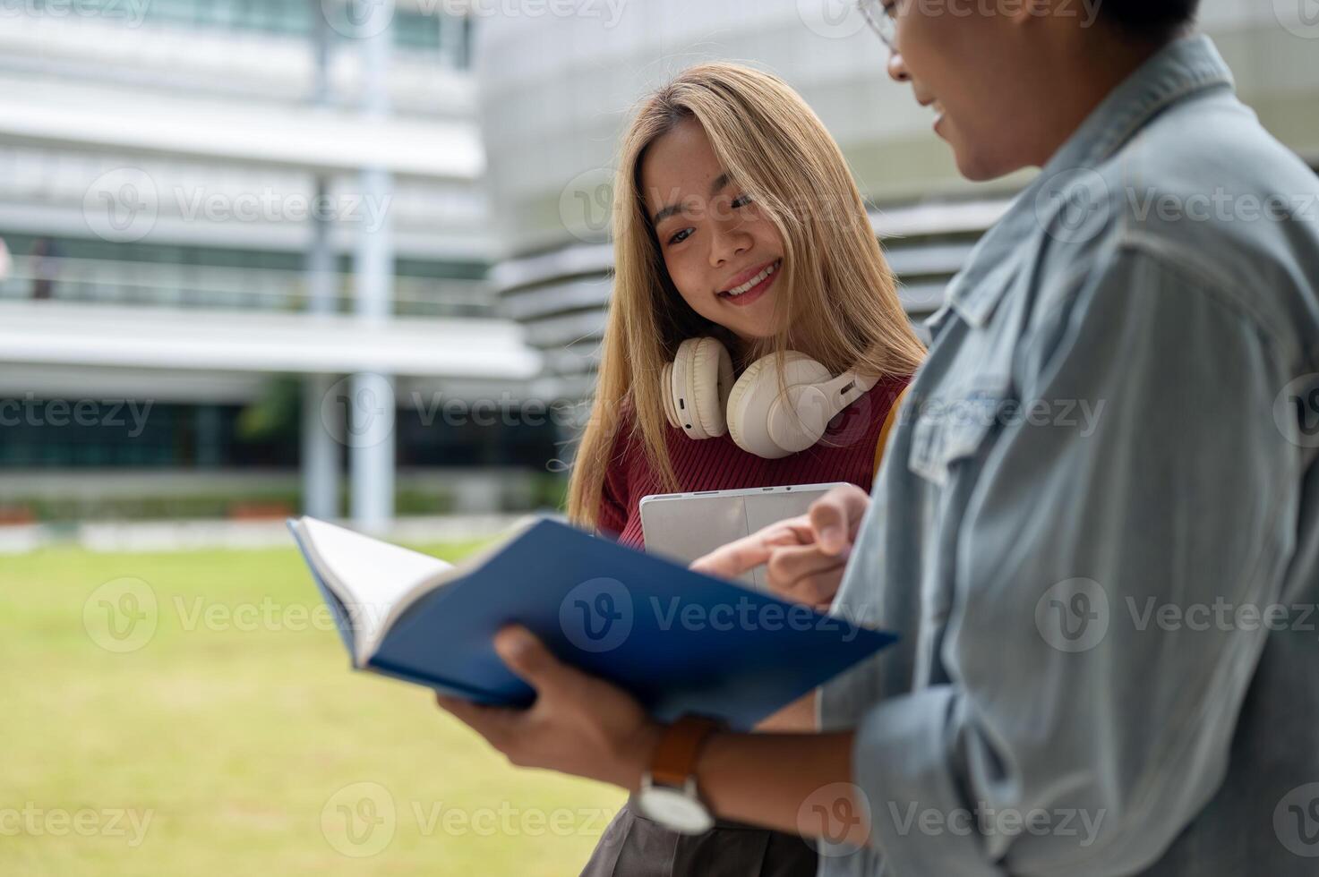 Two happy and cheerful young Asian college students are looking at a book and discussing homework. photo