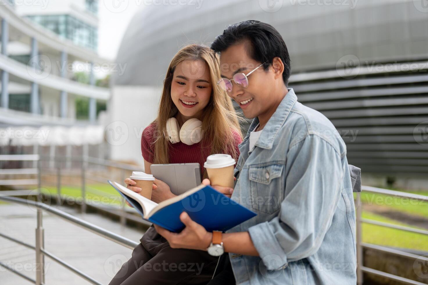 A lovely Asian female college student is reading a book with her friend in a campus outdoor hallway. photo