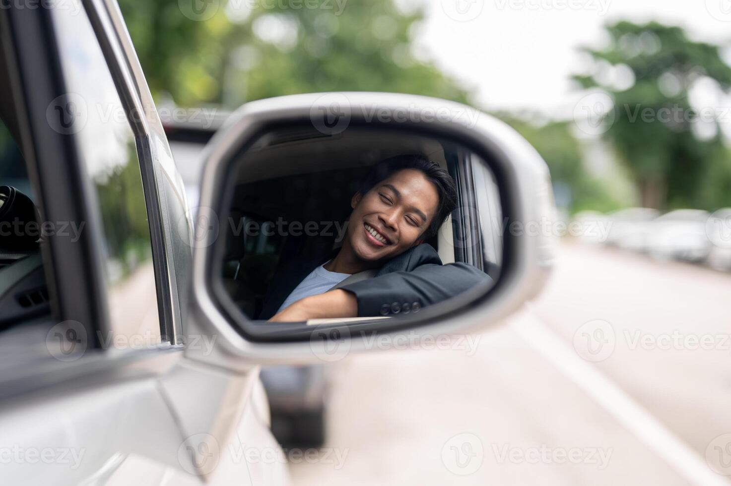 A close-up image of a car's wing mirror with a man in a business suit smiling in the reflection. photo