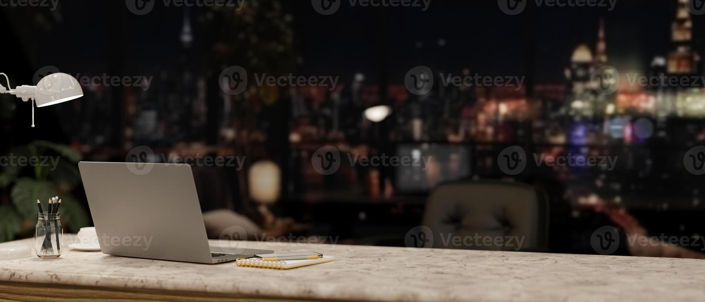 A modern office at night with a city view, featuring a laptop and accessories on a desk. photo