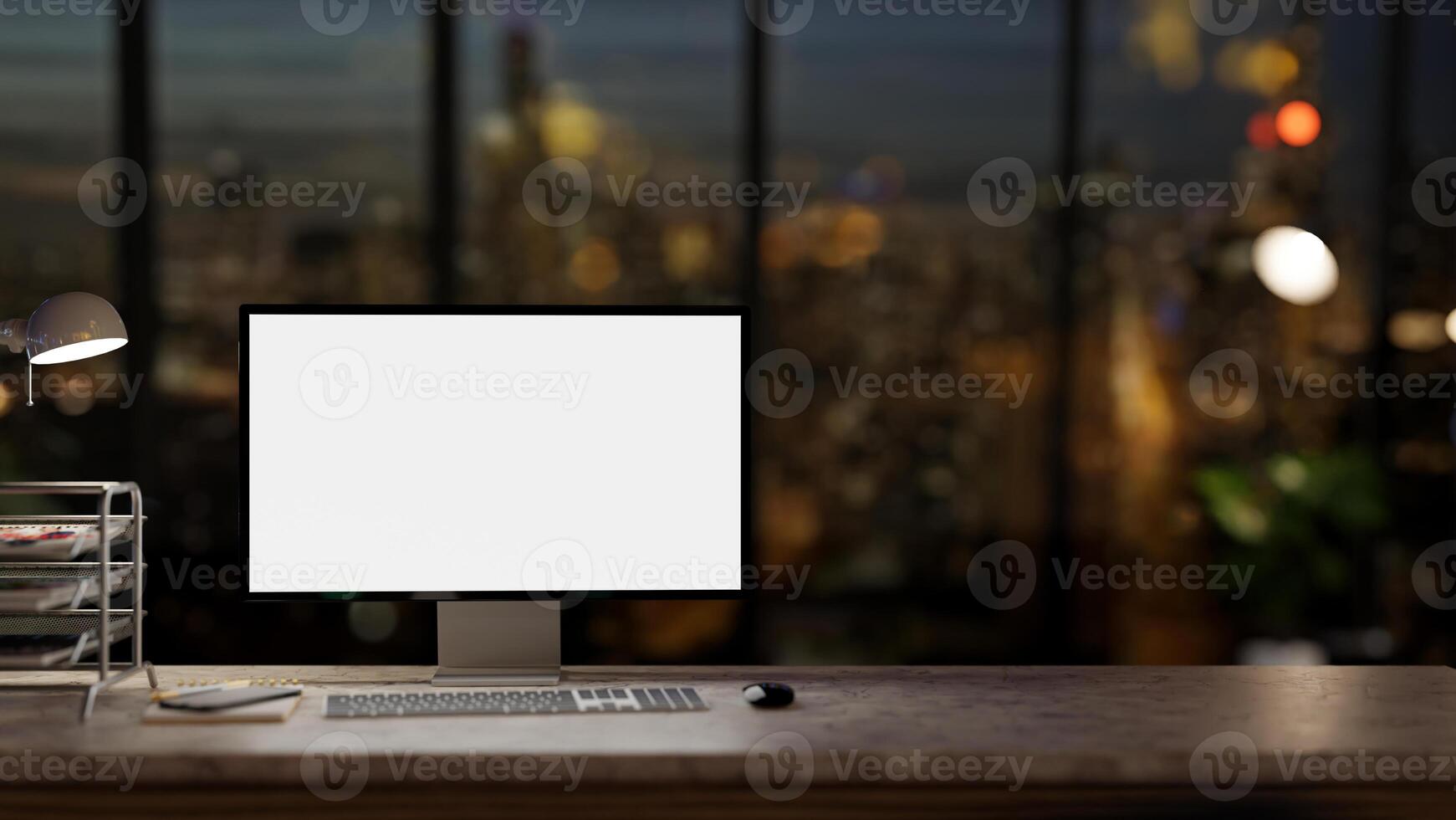 A computer desk in a modern dark office at night with a city view through the large glass window. photo