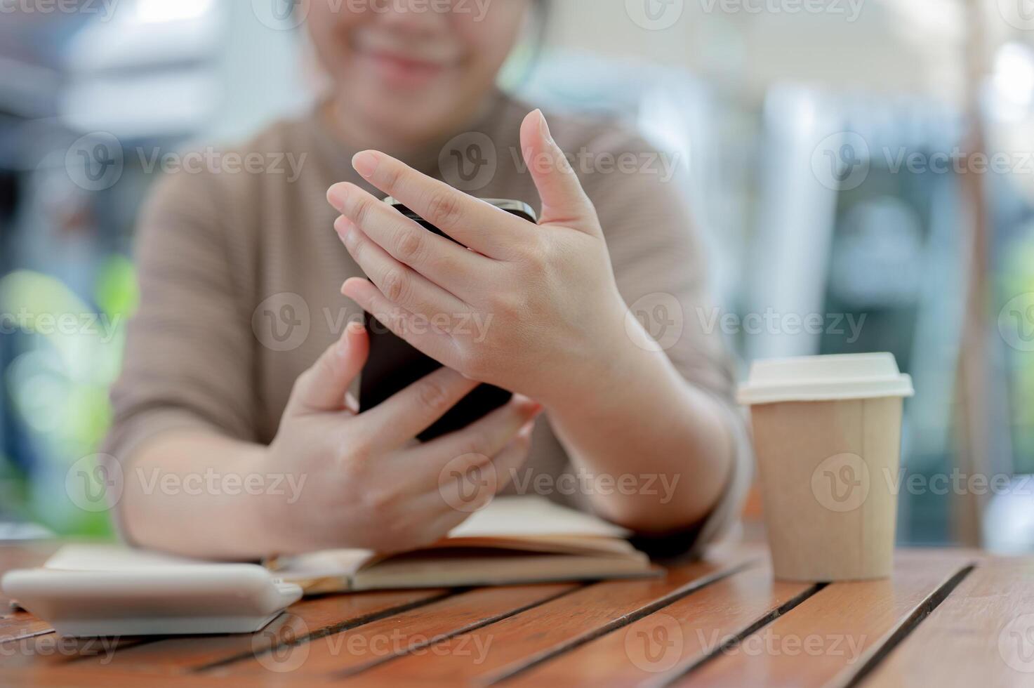 A cropped shot of a woman using her smartphone at a table in a cafe. photo