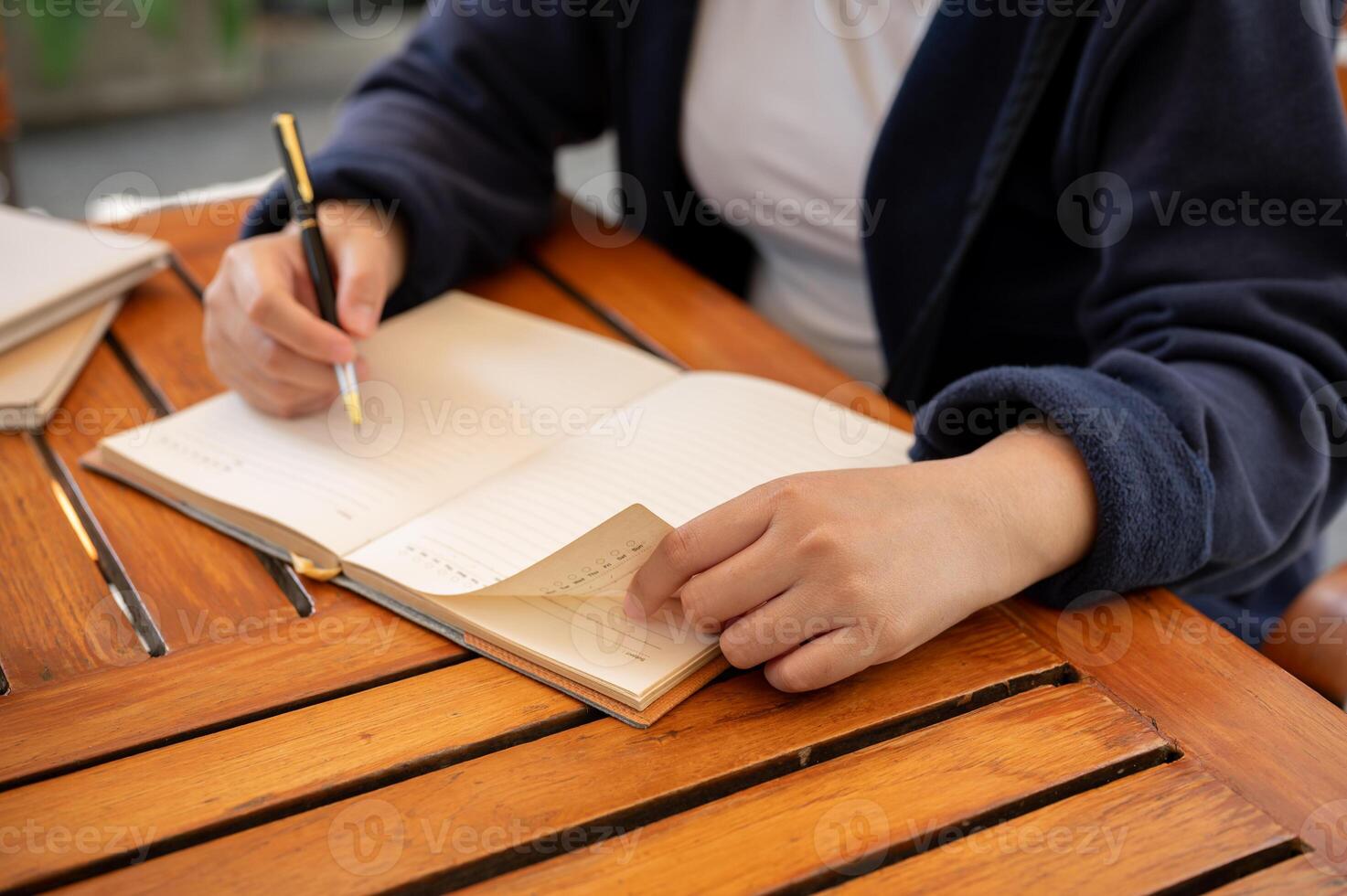 A cropped shot of a woman writing down her ideas in a book while sitting in a cafe. photo