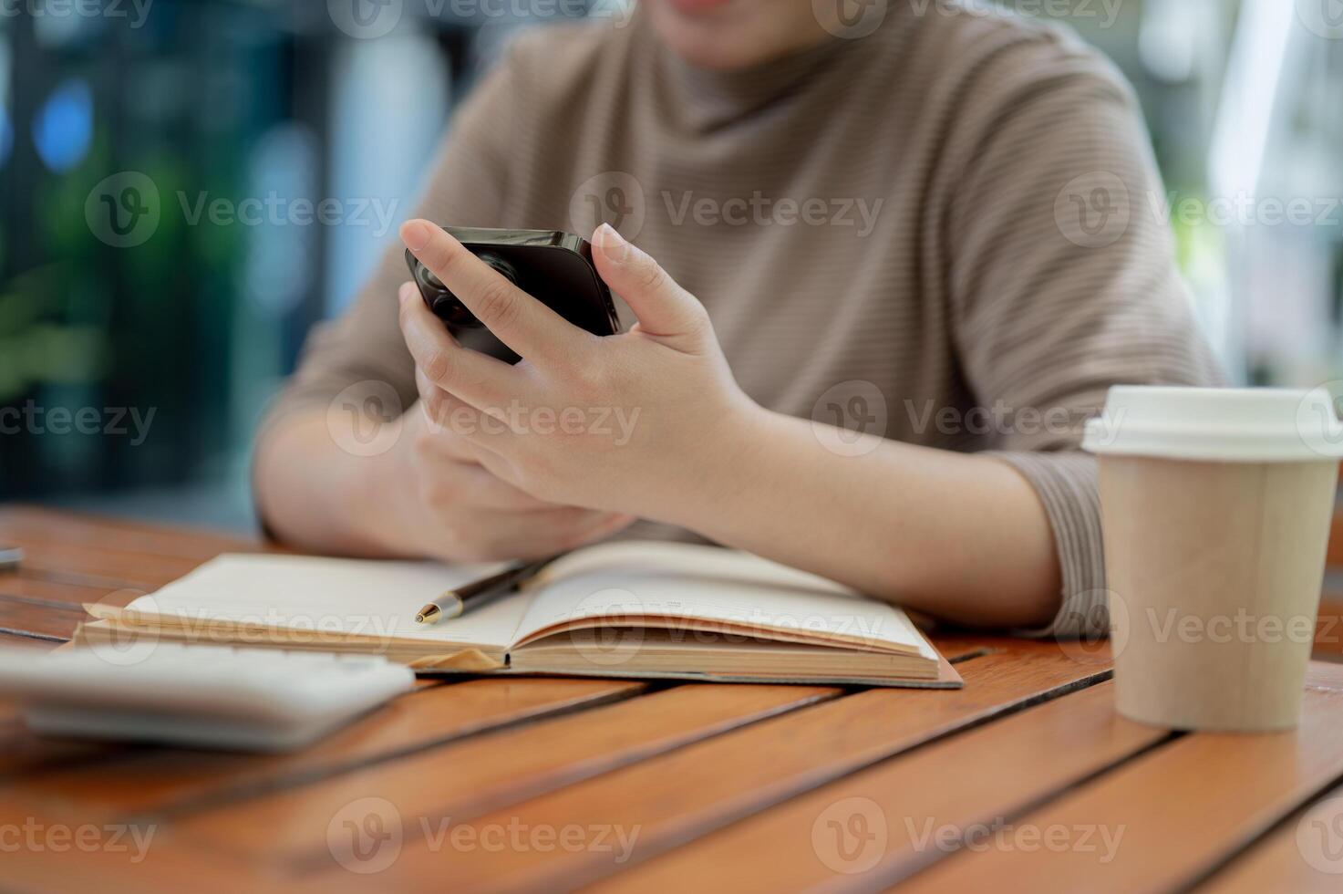 A cropped shot of a woman using her smartphone at a table in a cafe. photo