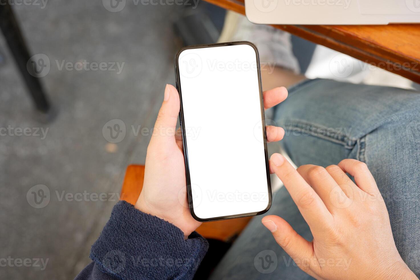 A close-up shot of a woman in casual clothes sitting in a cafe and using her smartphone. photo