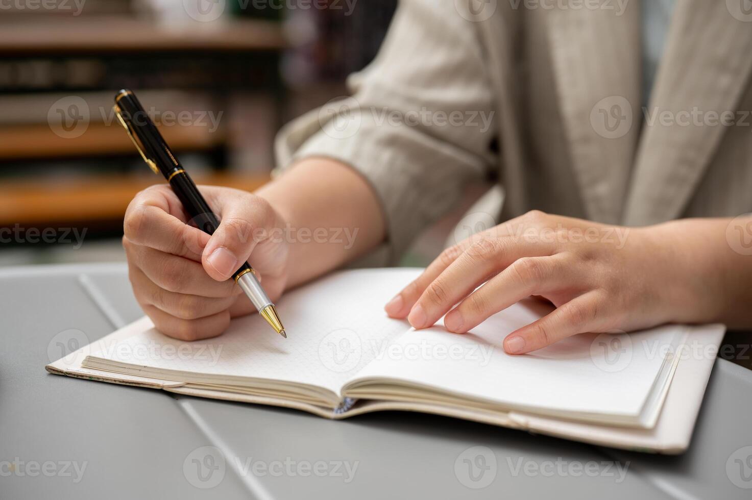 A businesswoman taking notes or writing something in her book while working remotely at a cafe. photo