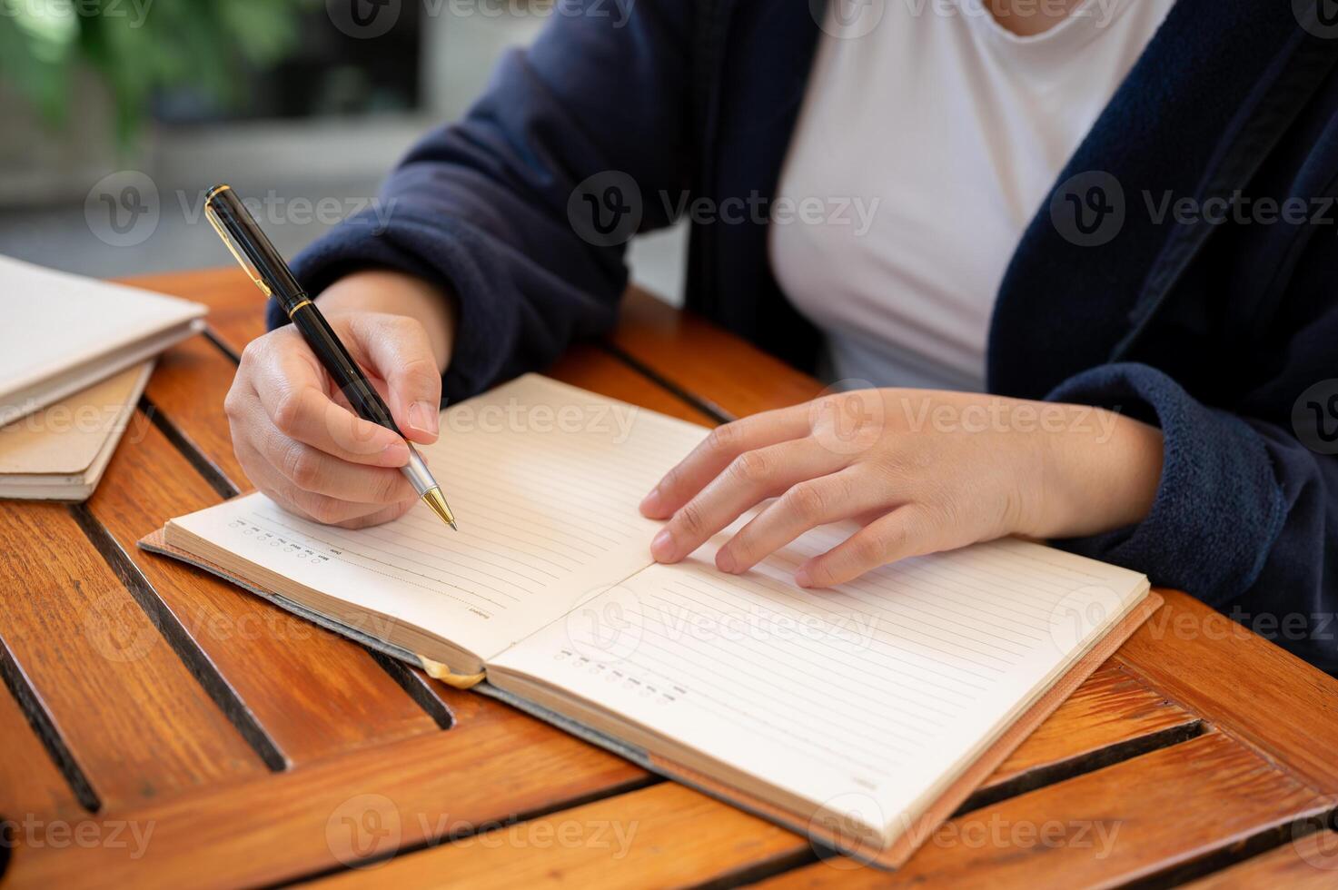 A cropped shot of a woman writing down her ideas in a book while sitting in a cafe. photo