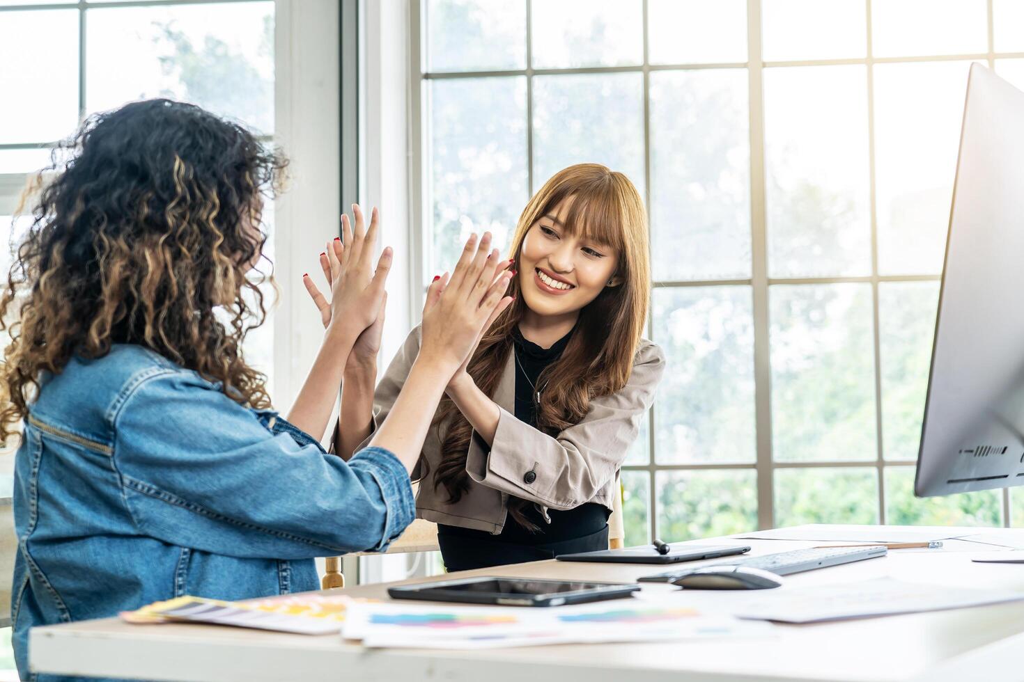 Collaboration of graphic design business people with computer in an office company. Two corporate women in creative marketing team working on project management , high five after a job is completed photo
