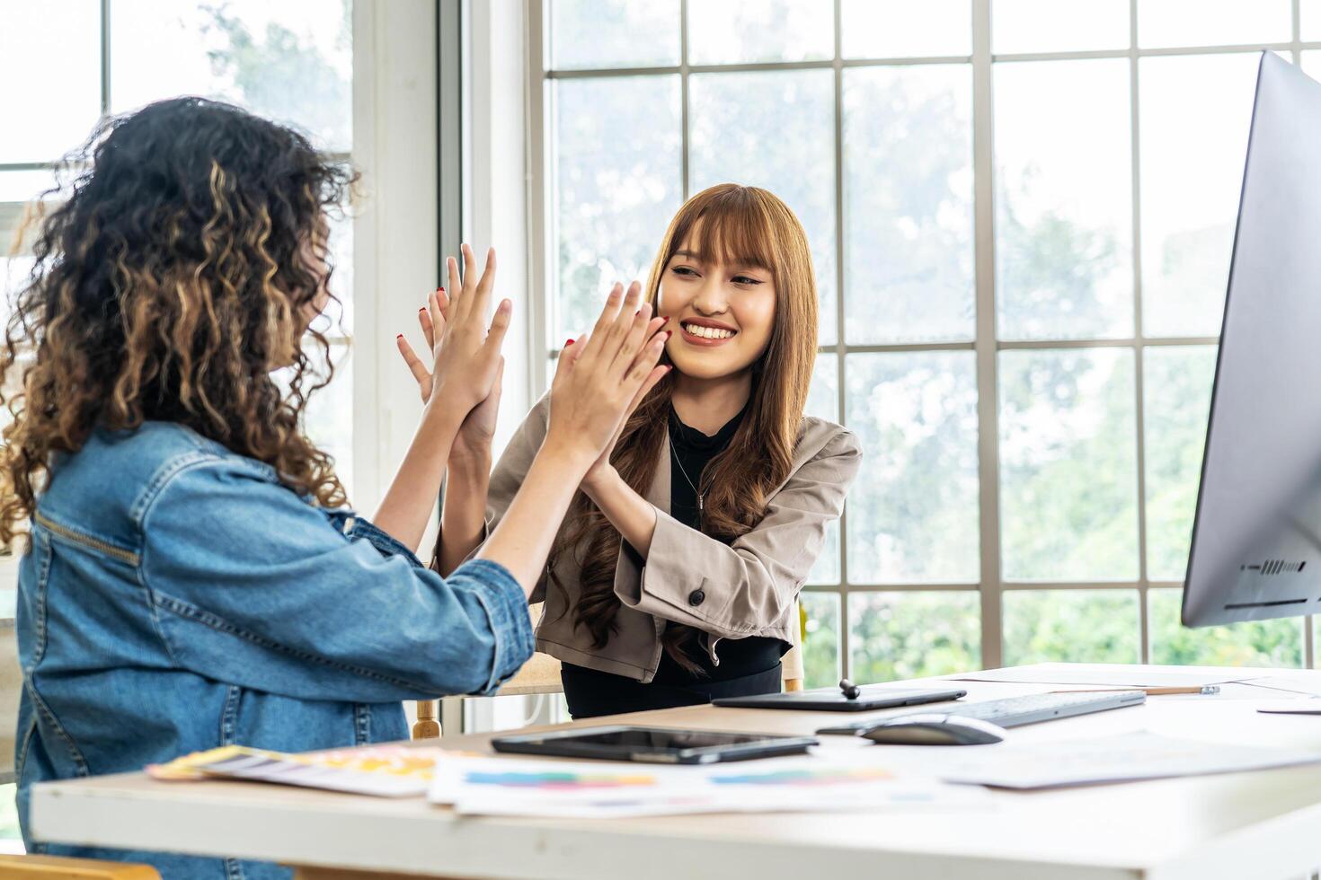 Collaboration of graphic design business people with computer in an office company. Two corporate women in creative marketing team working on project management , high five after a job is completed photo