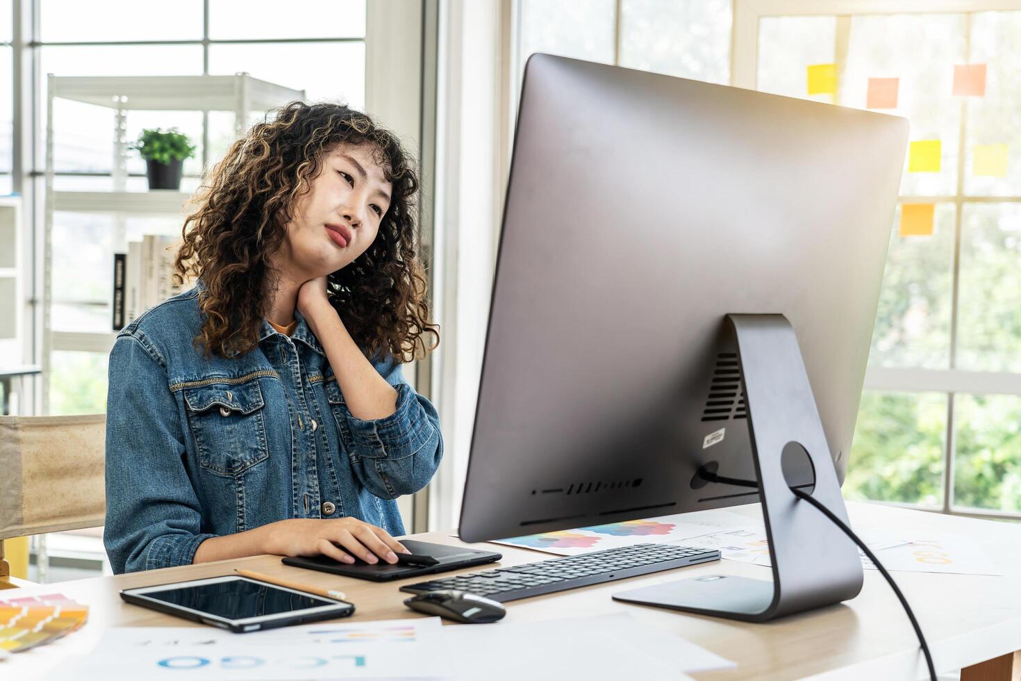 Tired fatigued asian girl feel neck discomfort with computer work in office, Young Asia girl development programmer overworked tired painful shoulder neck muscle from office syndrome photo