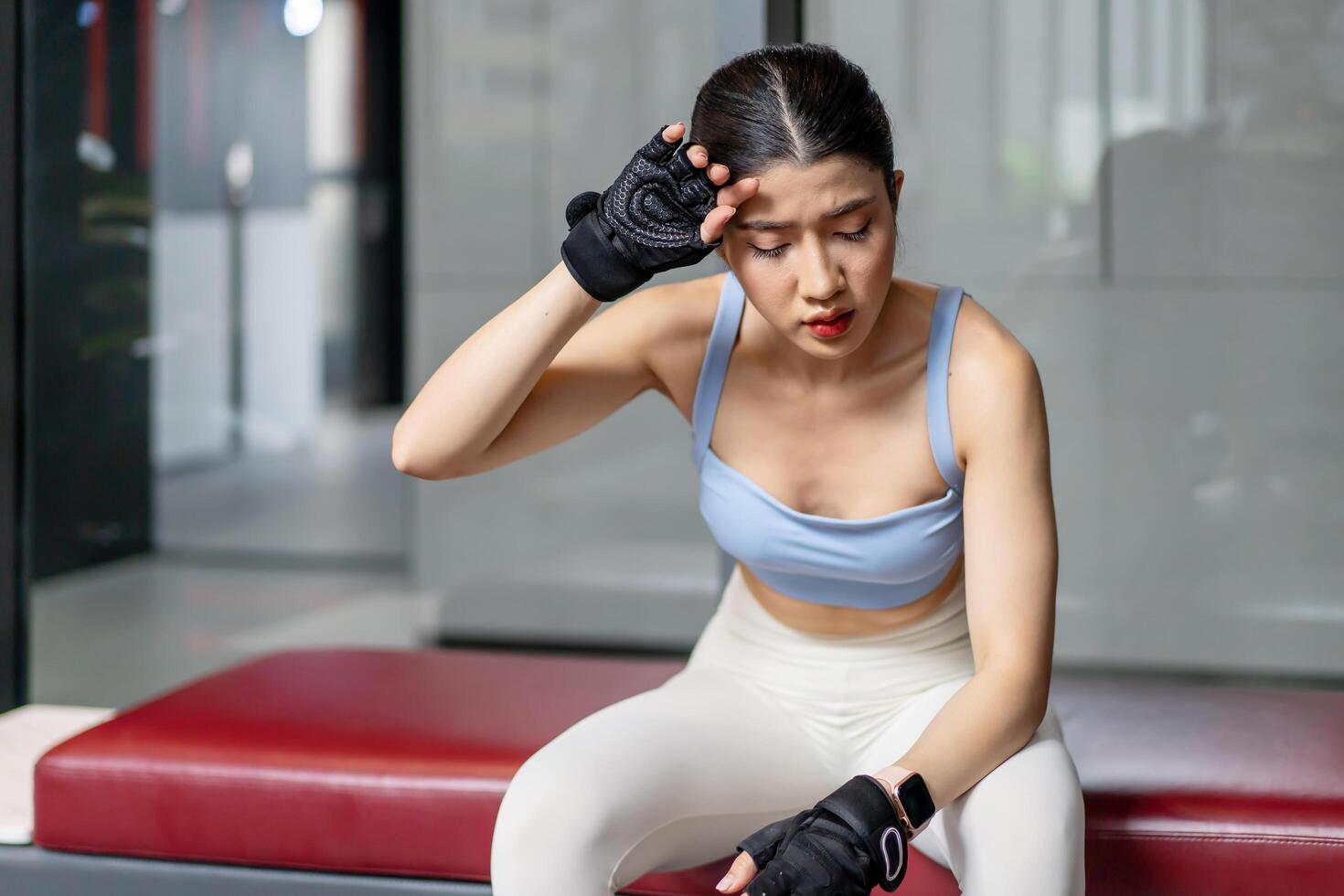 Portrait young asian woman in gym after workout, tired have sweaty and shortness of breath after physical training or exercise to burn energy, build muscle strength on training class in fitness. photo