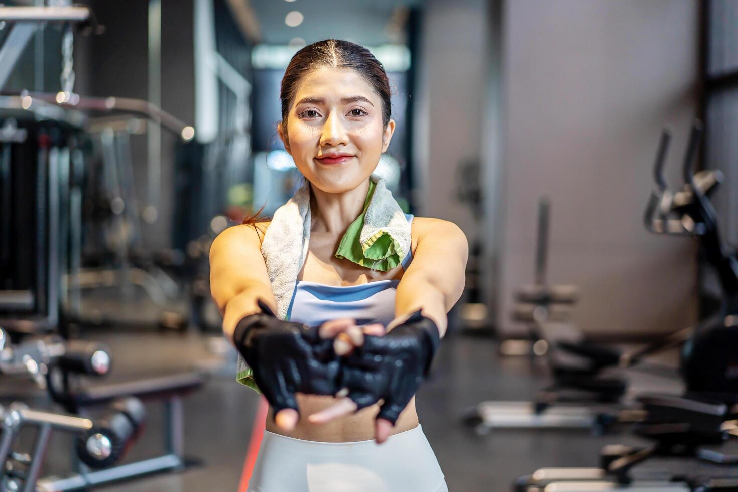 Active young Asian woman stretching her body warm up before intensive workout at gym, basic gym exercises performed by the young female photo