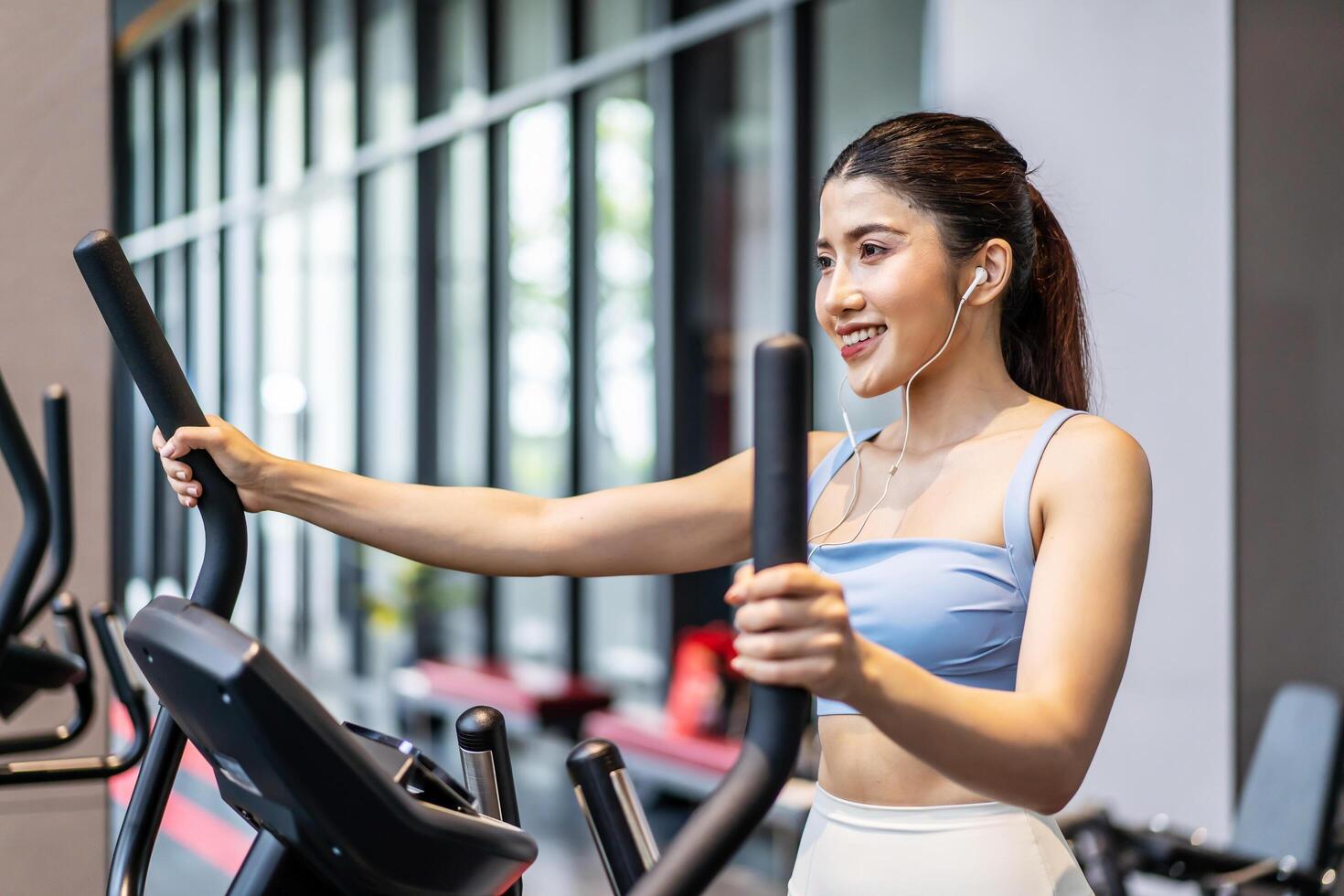 Young asian girl jogging on a treadmill in a gym, Muscular athletes actively training in the gym, Female training at fitness center. Woman exercising cardio workout, exercise lose weight, listen music photo