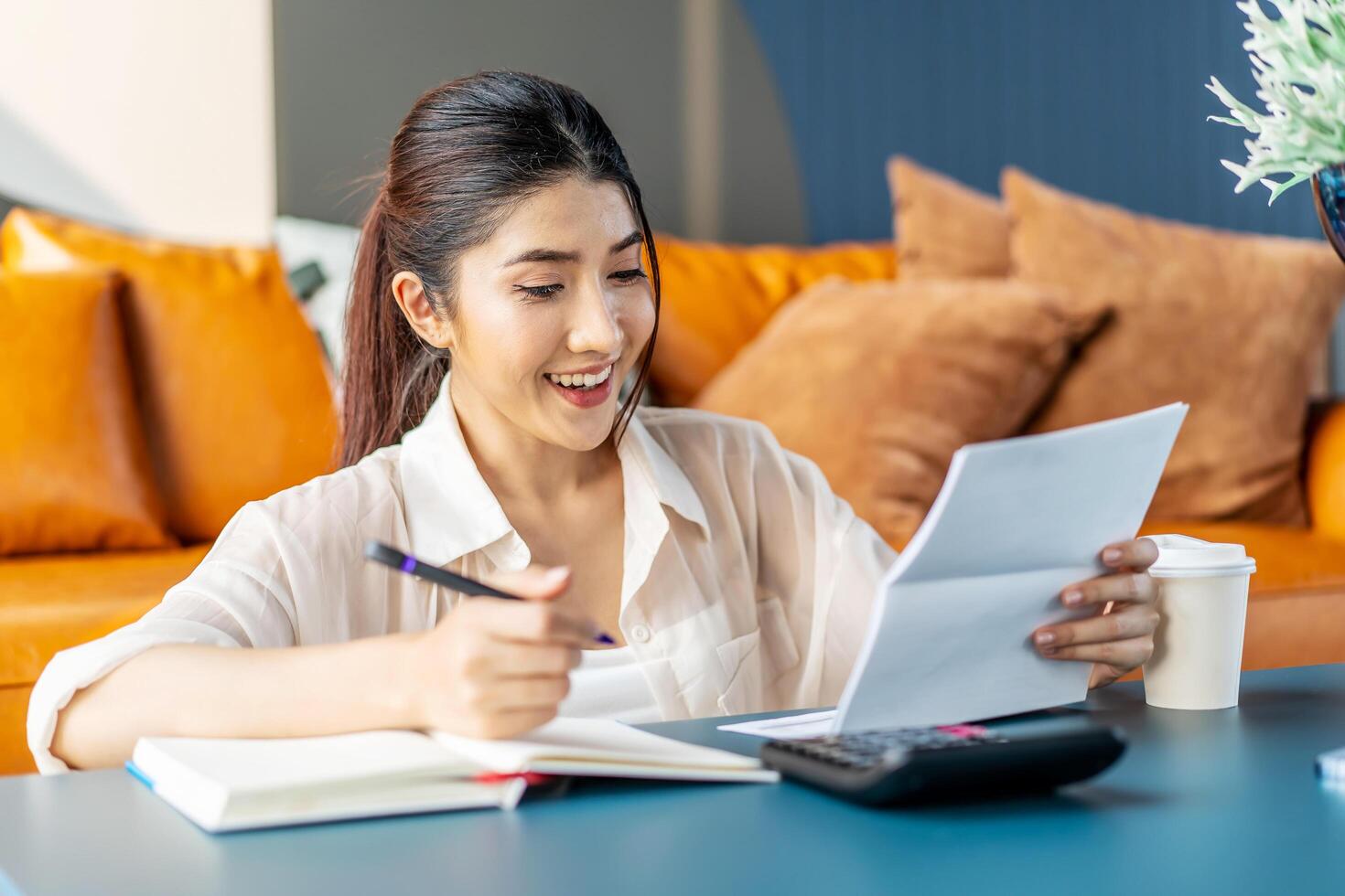 Smiling young asian woman hand press calculator to calculate income expenses and plans for spending money, checking bills, bank account balance and calculating expenses, enjoy profitable business photo