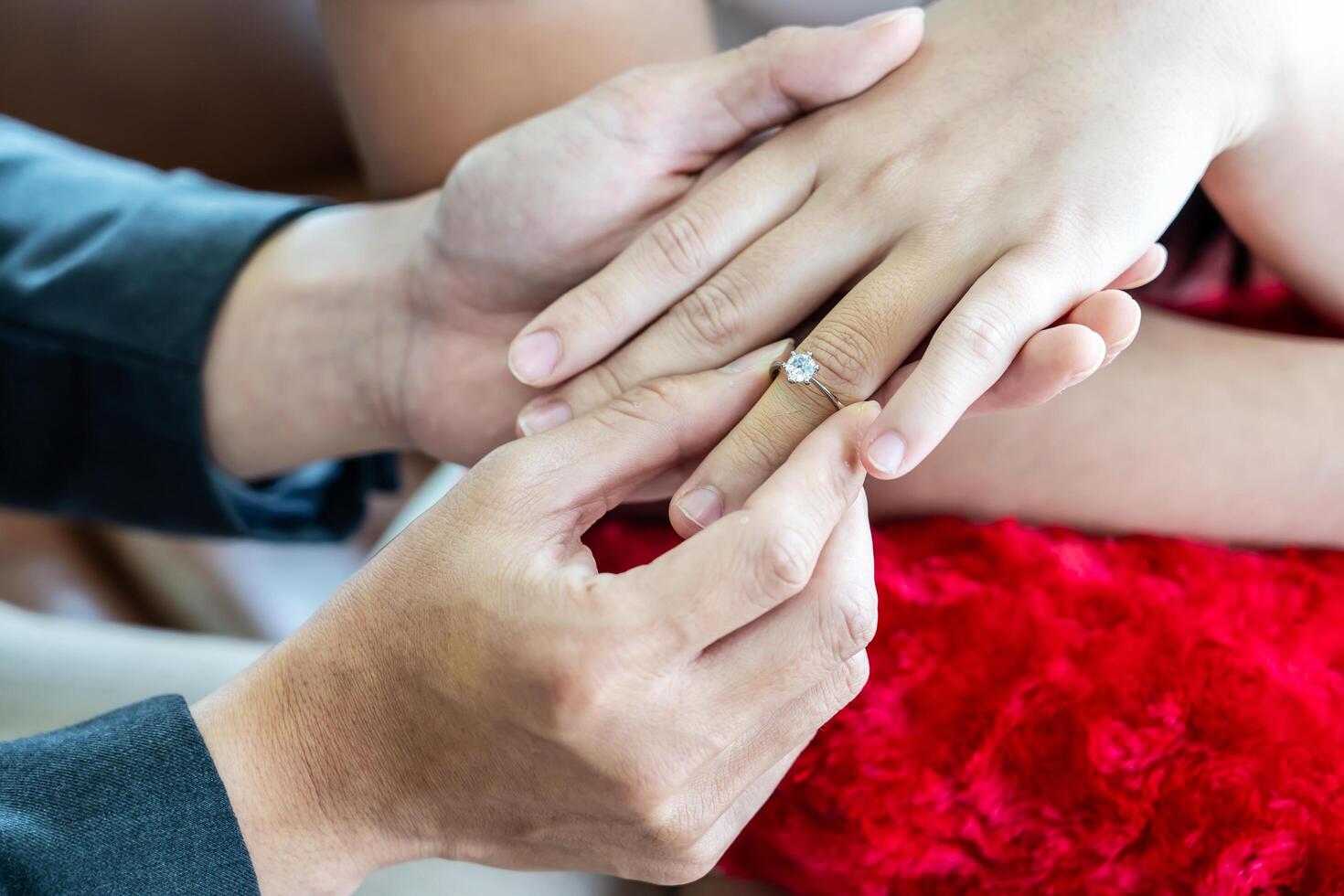 Close up of hand man putting ring on womans finger, boyfriend making marriage proposal proposing to girlfriend, casual couple getting married engaged, become husband wife, engagement wedding concept photo