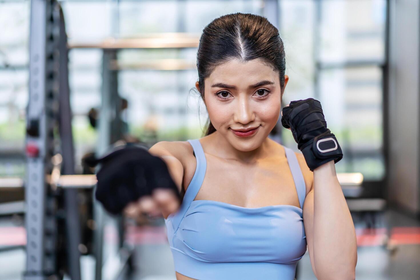Smiling asian athletic woman punching the air with her fists training warm-up before boxing workout at gym club. Sports. Activity. Motivation. Confidence, working out on boxing moves. photo