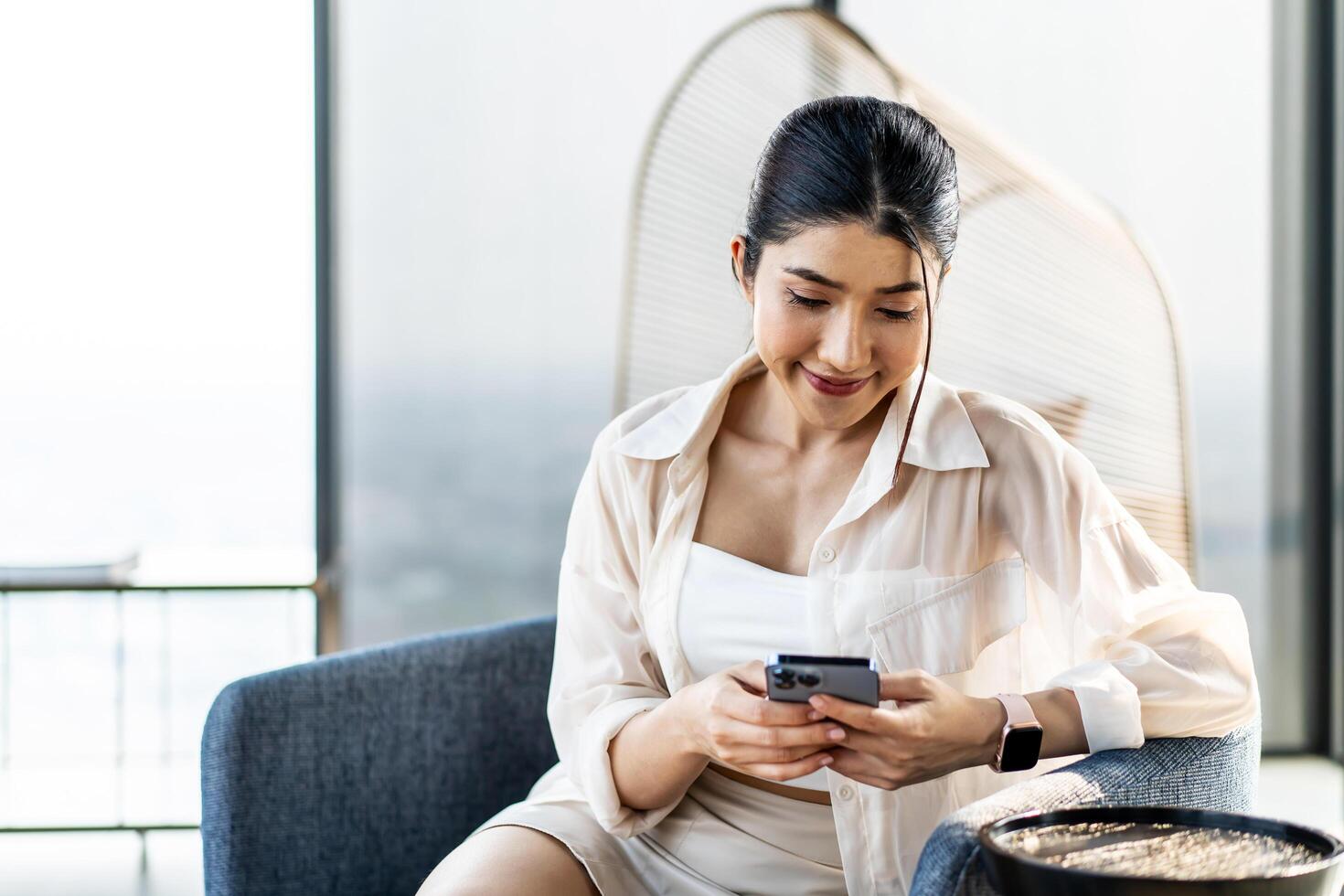 Smiling asian woman hold use smart phone sitting at home. watching social media. Portrait, entertainment, communication, work or study, connection, mobile apps, lifestyle concept. photo