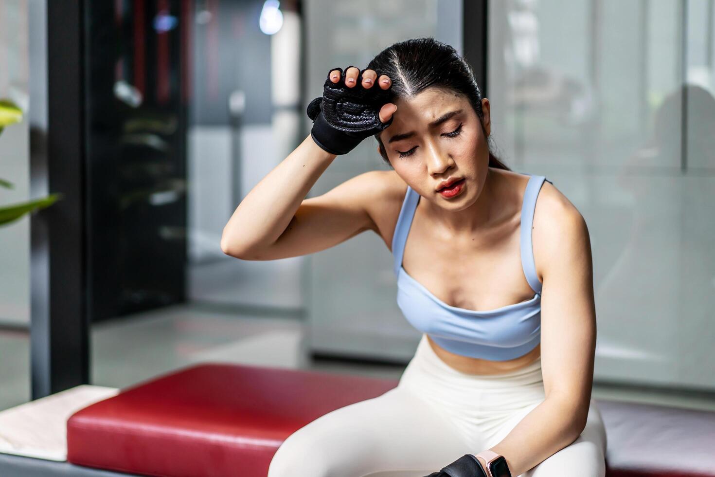 Portrait young asian woman in gym after workout, tired have sweaty and shortness of breath after physical training or exercise to burn energy, build muscle strength on training class in fitness. photo