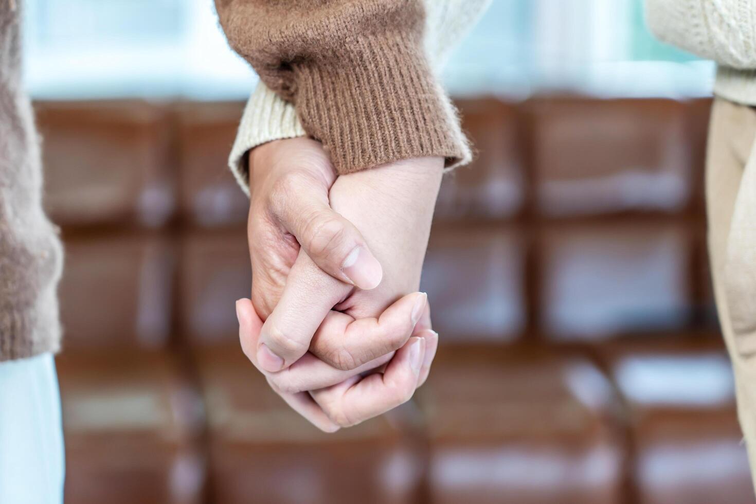 Close up of hand young happy loving couple guy and girl standing in front of big window, back to camera front view of an affectionate couple looking out of window while holding hand photo