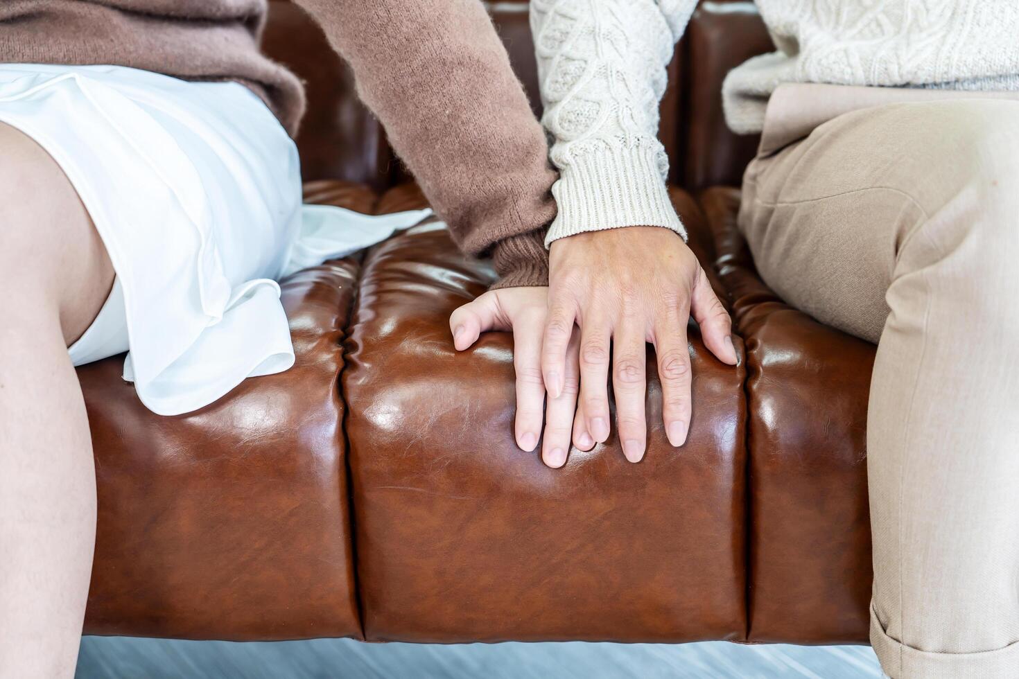 Closeup, couple and holding hands while resting on couch at home, to forgive, love and care with empathy at home. Life partner, helping hand and support of man, woman and hope for kindness photo