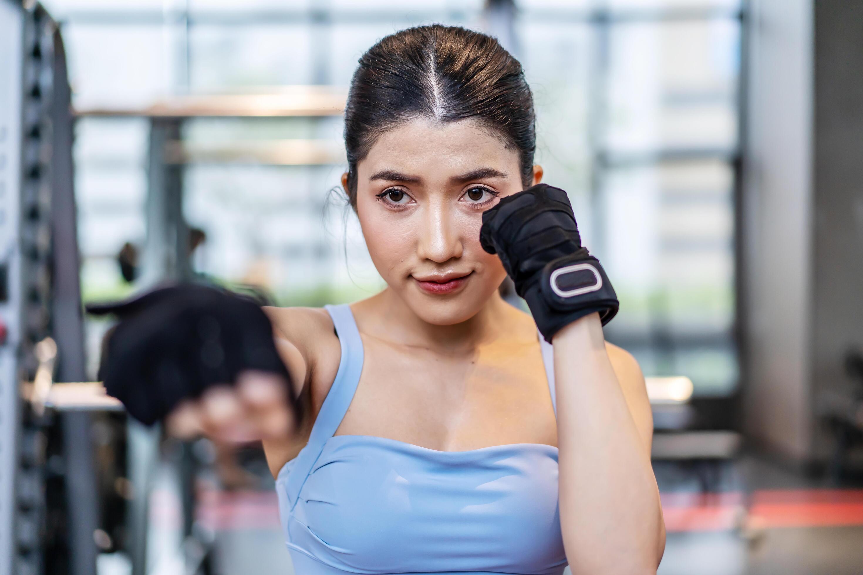Smiling asian athletic woman punching the air with her fists training warmup before boxing