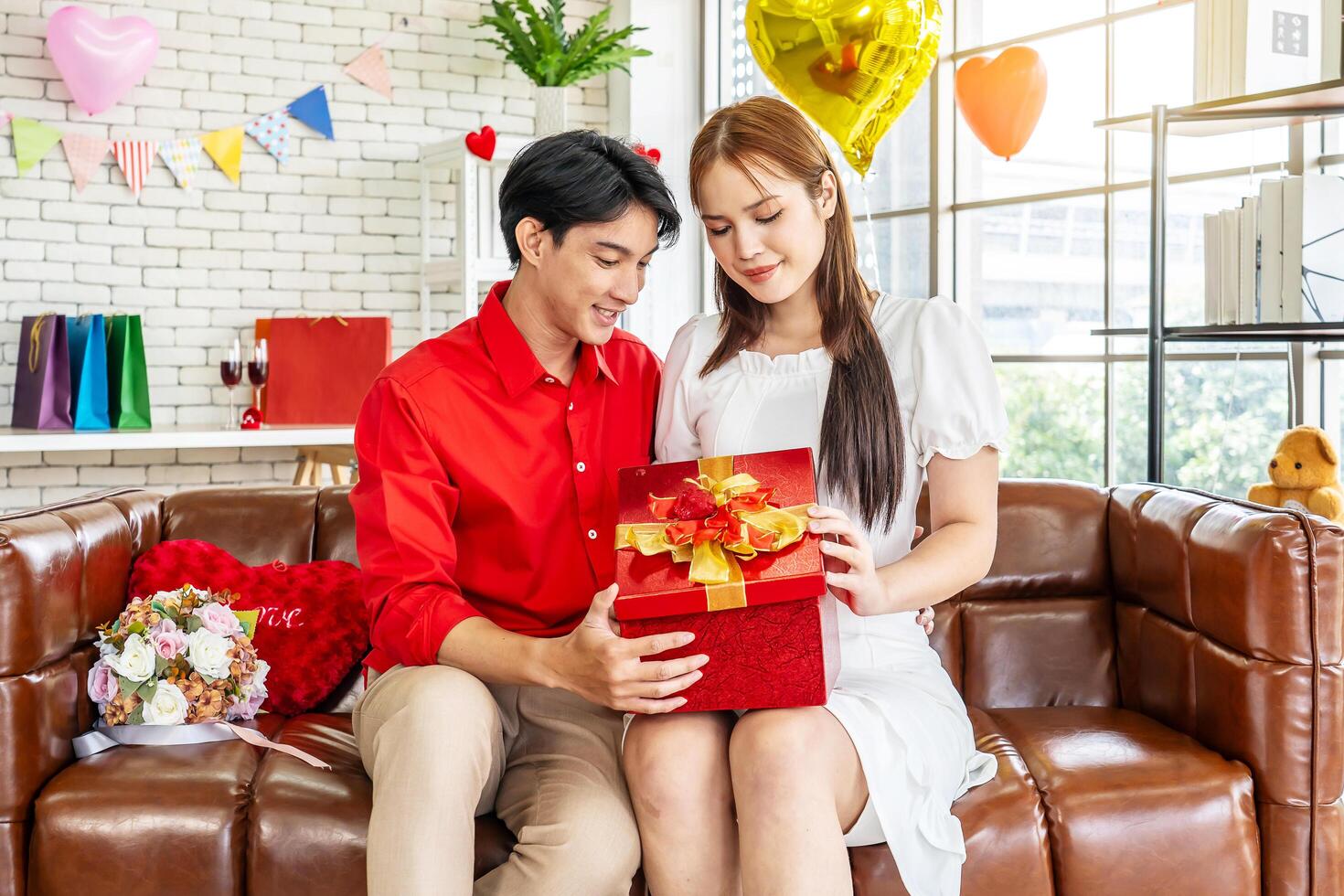 Excited young asian woman opening gift box receiving good unexpected present from husband at home, loving generous boyfriend making romantic surprise to attractive girlfriend on Valentines day photo