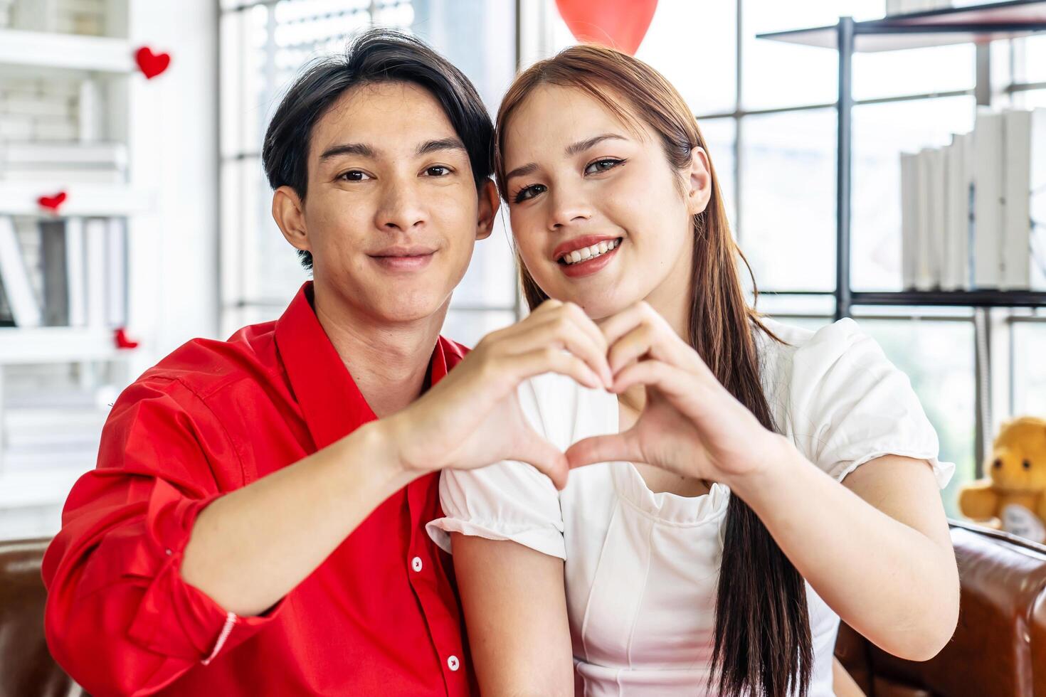Love, happy and hand heart by couple on sofa with love, care and trust at home together. Emoji, shape and man with woman hands in support of hope, marriage and unity, smile and joy in living room photo