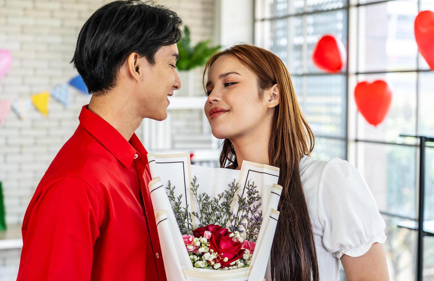 Young asian woman receives a bouquet of red roses as a gift from a man or boyfriend. Portrait of a young woman in the living room with a bouquet of flowers. Anniversary, Women's Day, Valentine's Day. photo