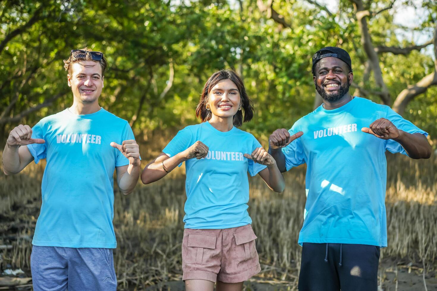 Group of multiethnic volunteers showing the lettering on t-shirts together in partnership teamwork smiling look at the camera in forests, Environmental protection, and ecology concept. photo