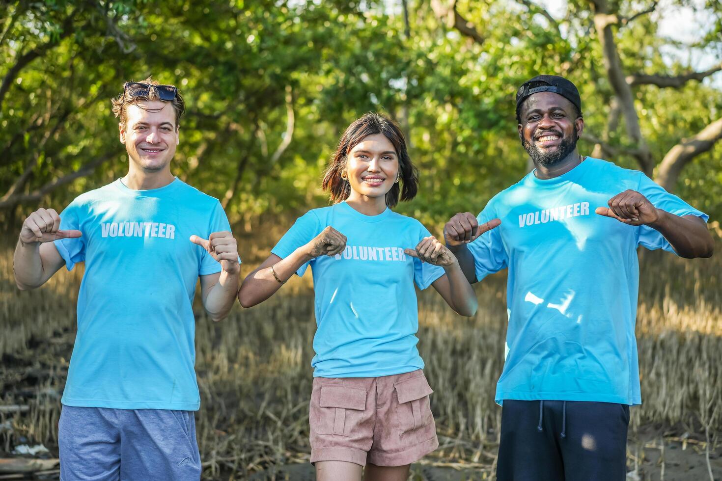 Group of multiethnic volunteers showing the lettering on t-shirts together in partnership teamwork smiling look at the camera in forests, Environmental protection, and ecology concept. photo