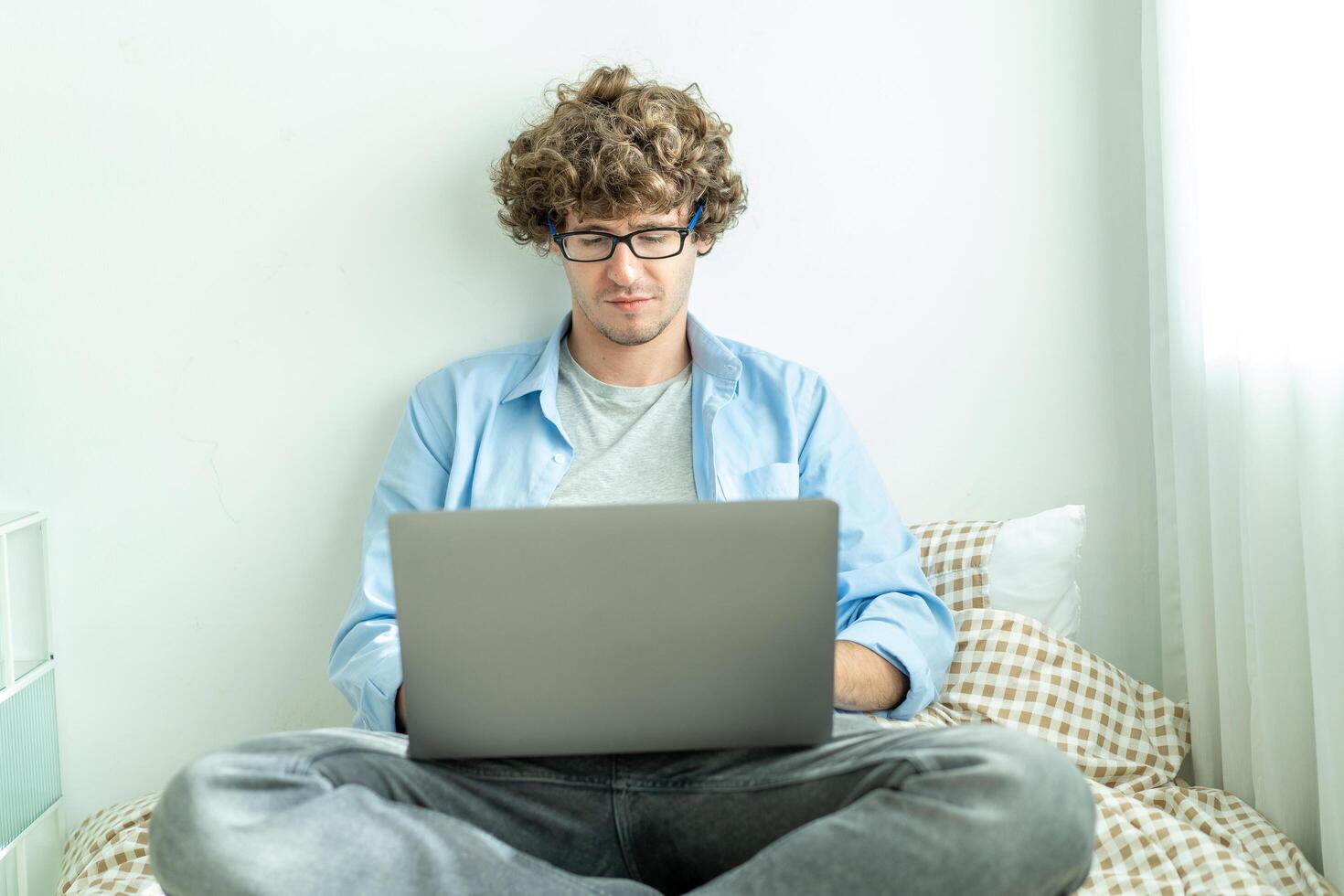 work from home. young caucasian man working on computer laptop. study online listening learning education course conference calling sit laying down on bed elearning concept, freelancer at home photo