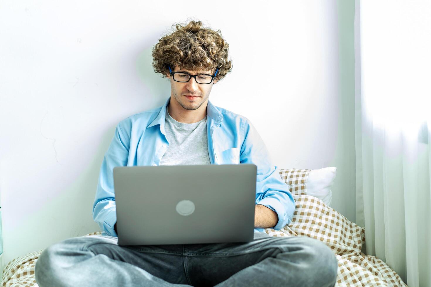 work from home. young caucasian man working on computer laptop. study online listening learning education course conference calling sit laying down on bed elearning concept, freelancer at home photo