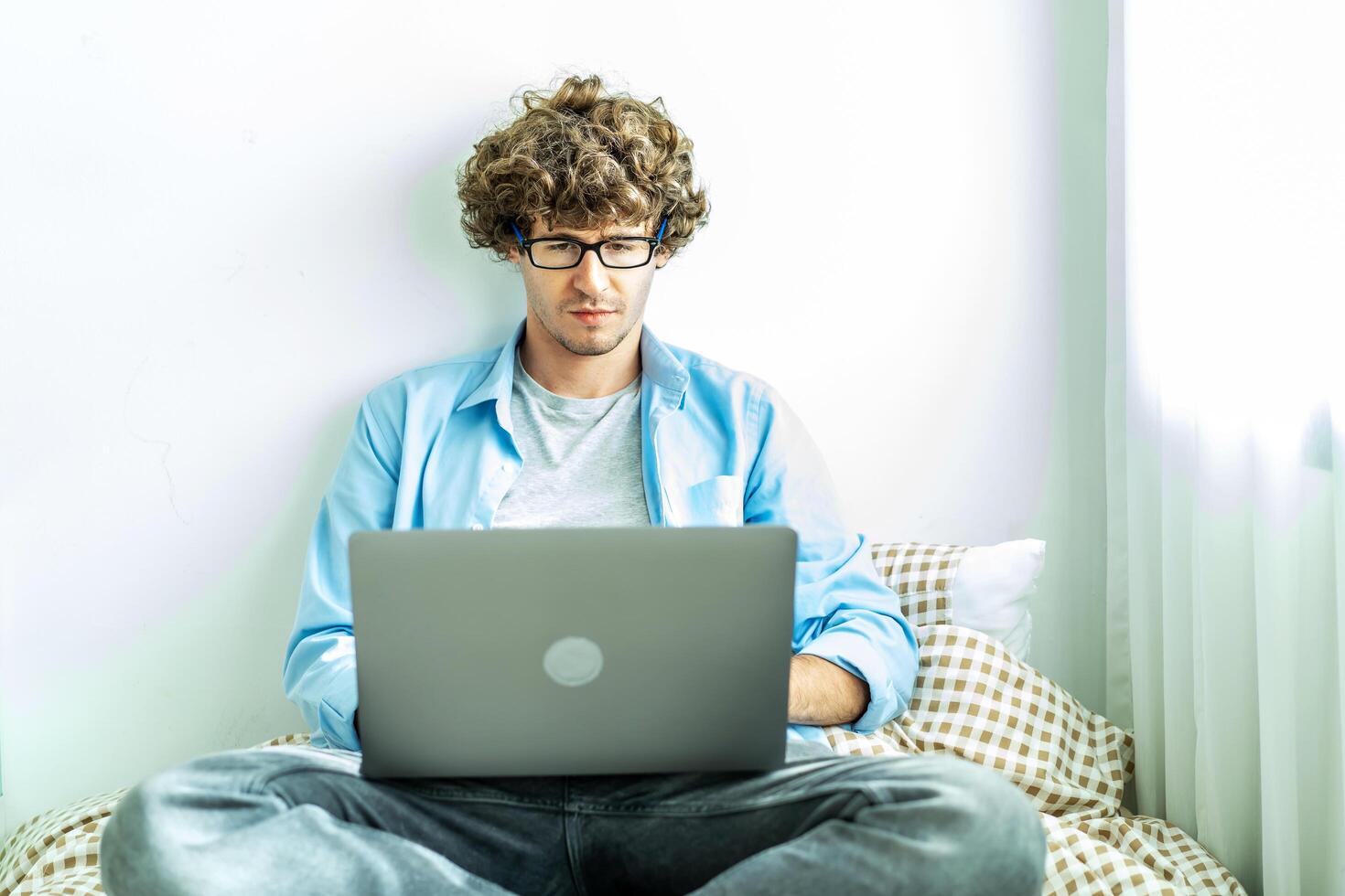 work from home. young caucasian man working on computer laptop. study online listening learning education course conference calling sit laying down on bed elearning concept, freelancer at home photo