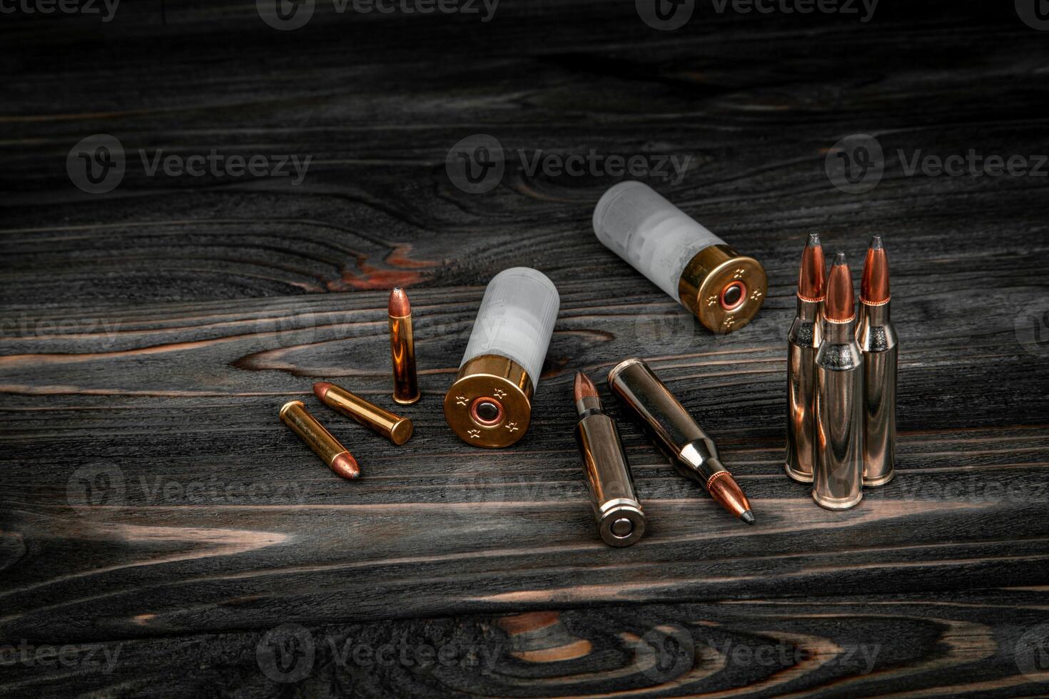 Various types of ammunition on a wooden surface. Cartridges for weapons. Dark back. photo