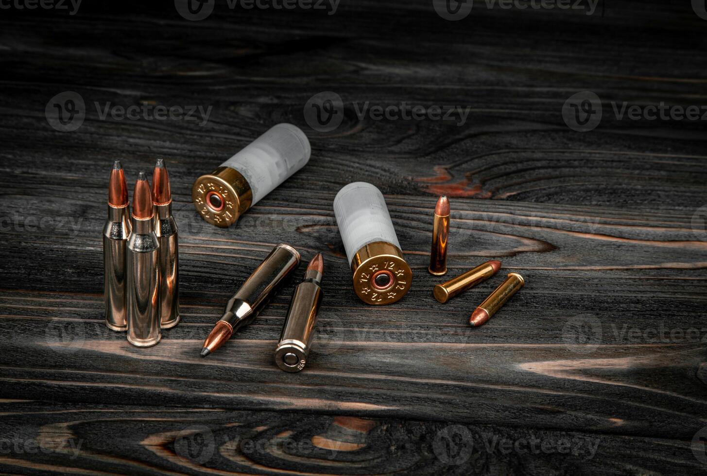 Various types of ammunition on a wooden surface. Cartridges for weapons. Dark back. photo