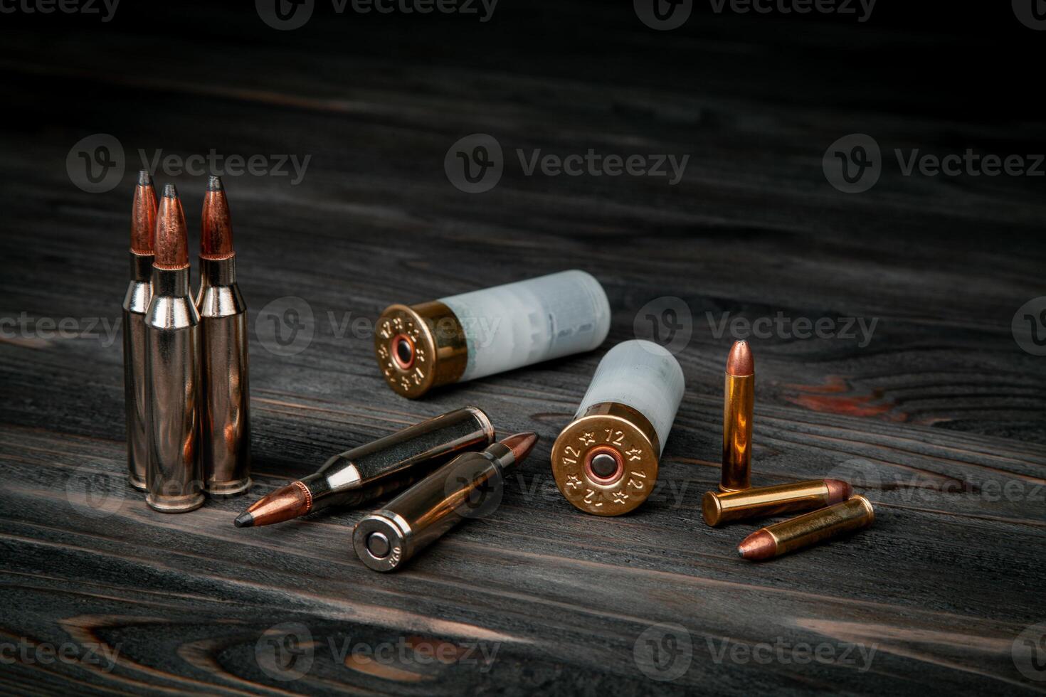Various types of ammunition on a wooden surface. Cartridges for weapons. Dark back. photo