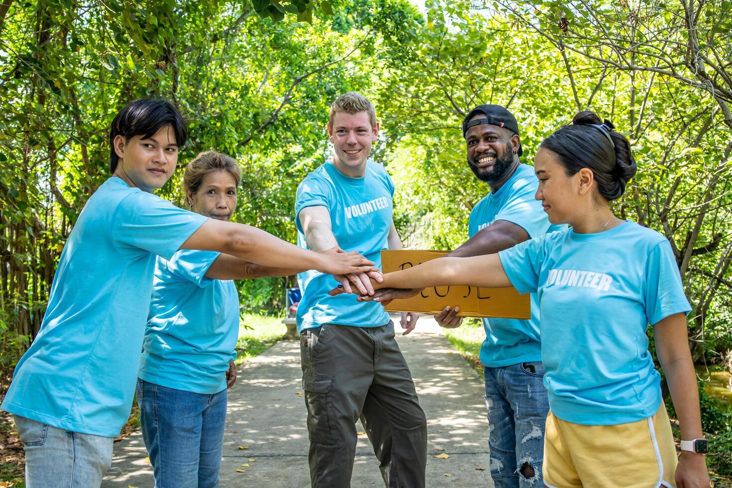 Group of volunteers stand to put your hands up and raise your hands together for help to save nature collecting garbage, Natural environment, pollution concept, Cleaning of nature from waste photo