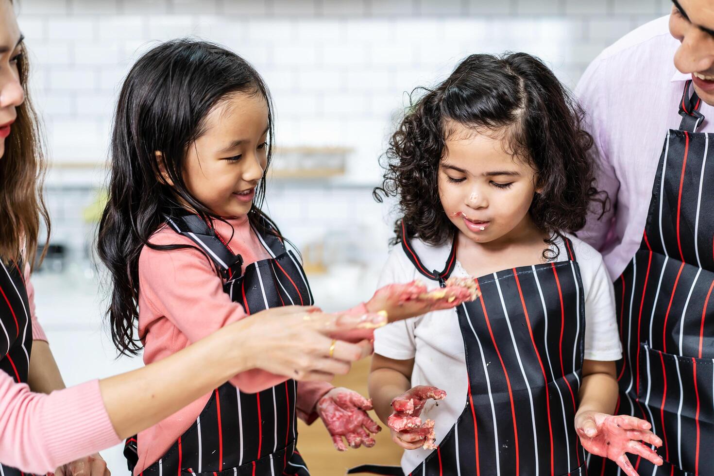 Group of three Diverse Family, Asian and Arab Preschool kid person make Cake cooking in kitchen, Mom dad and daughter getting dirty with flour while baking cakes together ,Cream mess over face photo