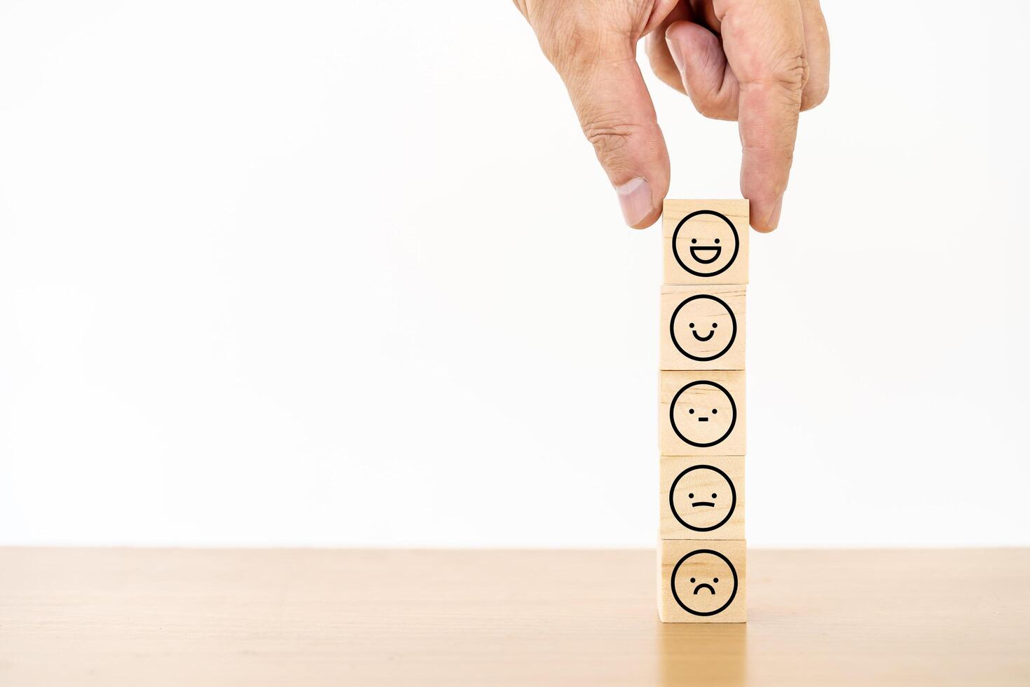 Hand of a businessman chooses a smiley face icon on wood block cube, The best excellent business services rating customer experience, Satisfaction survey concept, Service rating photo