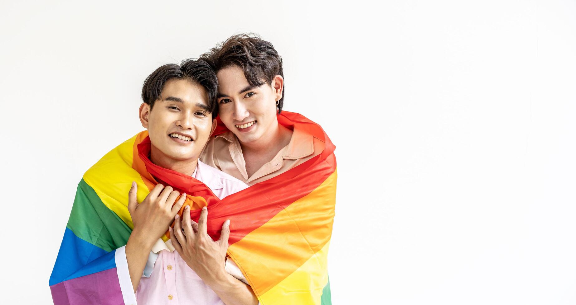 Guys spend time together at home, Portrait of Happy Asian gay couple embracing and showing their love under lgbt colorful rainbow flag. LGBT and love concept. photo