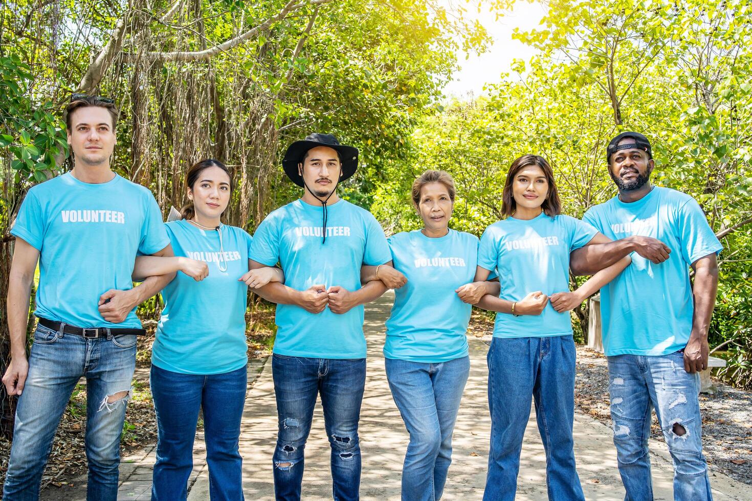 Portrait of smiling male and female volunteers standing with arms around. Multiracial group of confident activists are in park. They are volunteering for environmental cleanup. photo