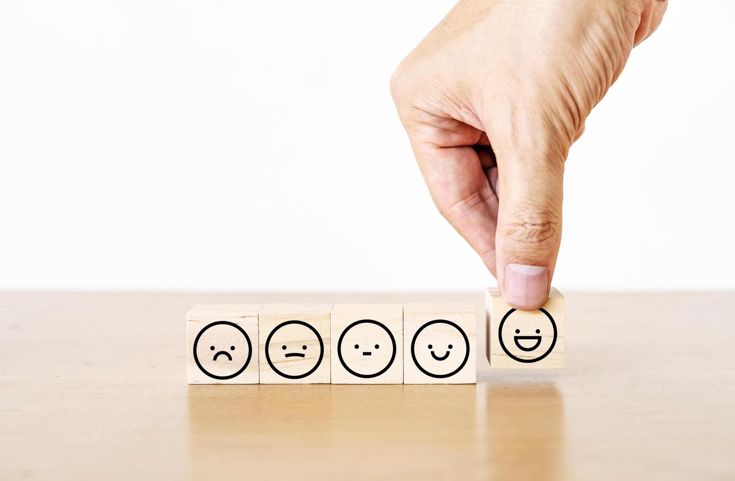 Hand of a businessman chooses a smiley face icon on wood block cube, The best excellent business services rating customer experience, Satisfaction survey concept, Service rating photo