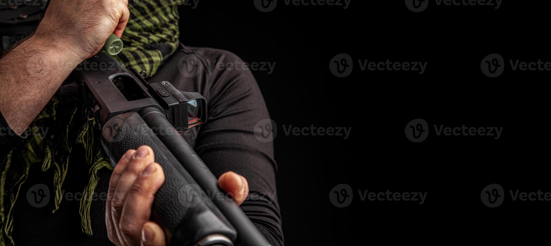 The man charges the shotgun with ammunition. Charging a pump smoothbore weapon. Close-up photo. photo