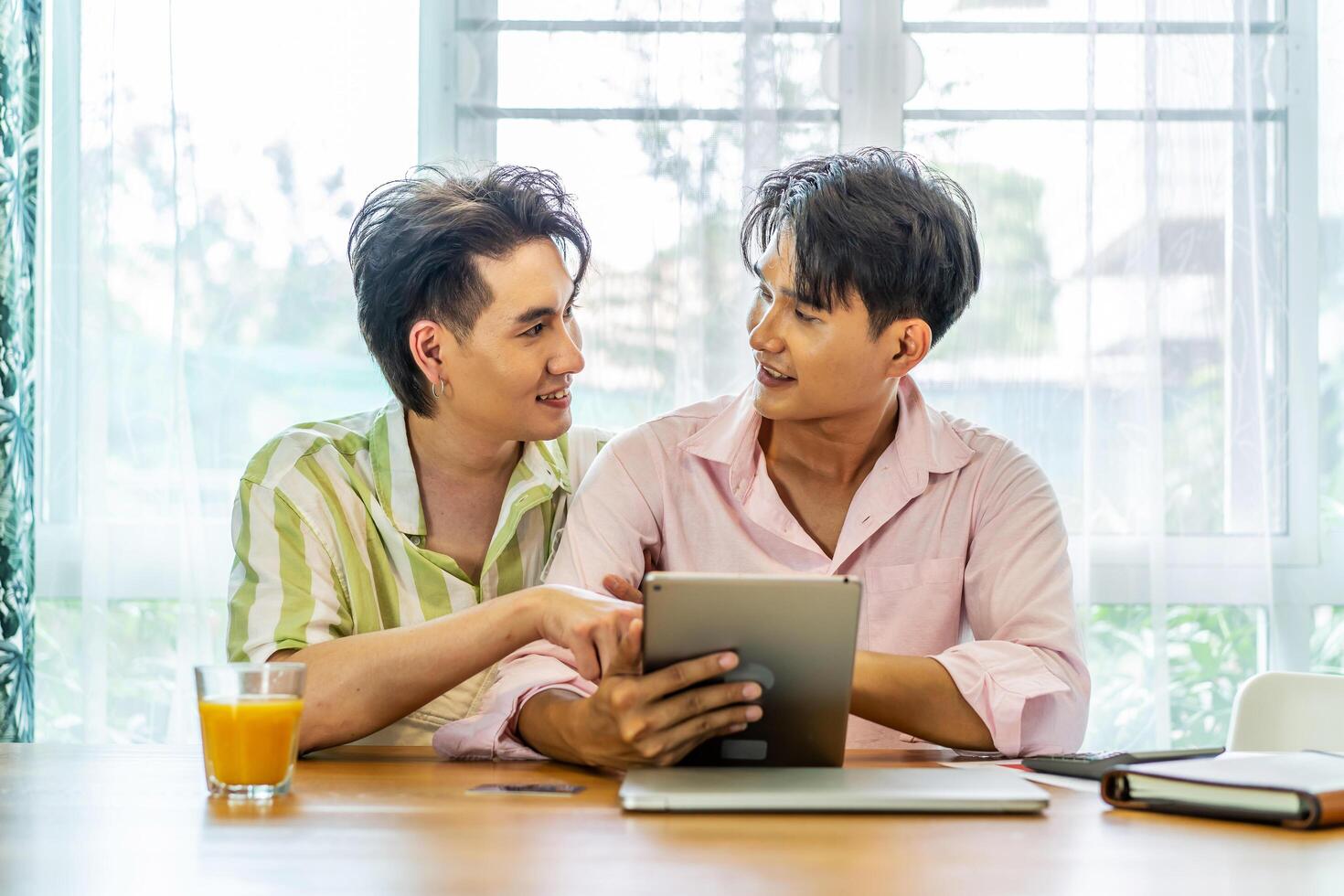 Attractive male lgbtq collegues working together with using digital tablet and paper showing graphic chart in living room, Lgbt love concept photo