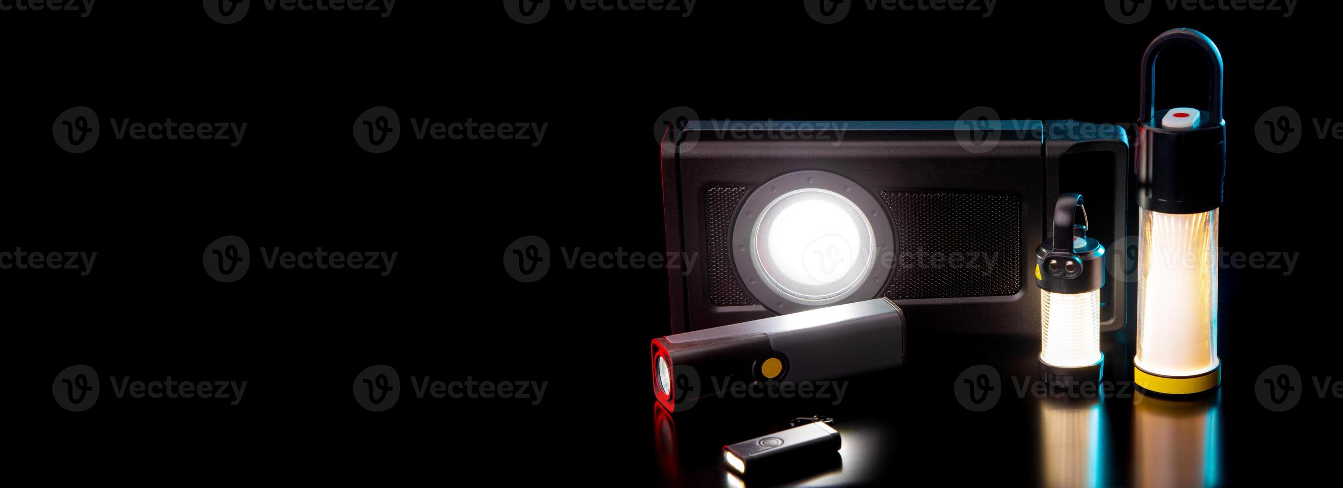 Modern metal LED flashlight in black color. A variety of portable lanterns on a dark back. photo