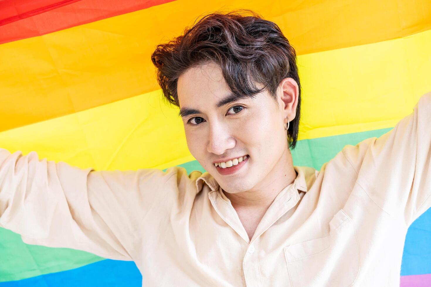 Portrait of transgender or gay man smiling in front of camera with pride rainbow flag isolated on white background with copy space. People lifestyle fashion lgbtq concept photo