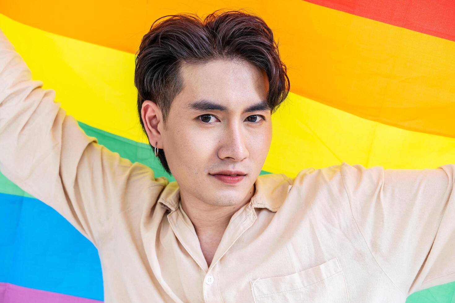 Portrait of transgender or gay man smiling in front of camera with pride rainbow flag isolated on white background with copy space. People lifestyle fashion lgbtq concept photo