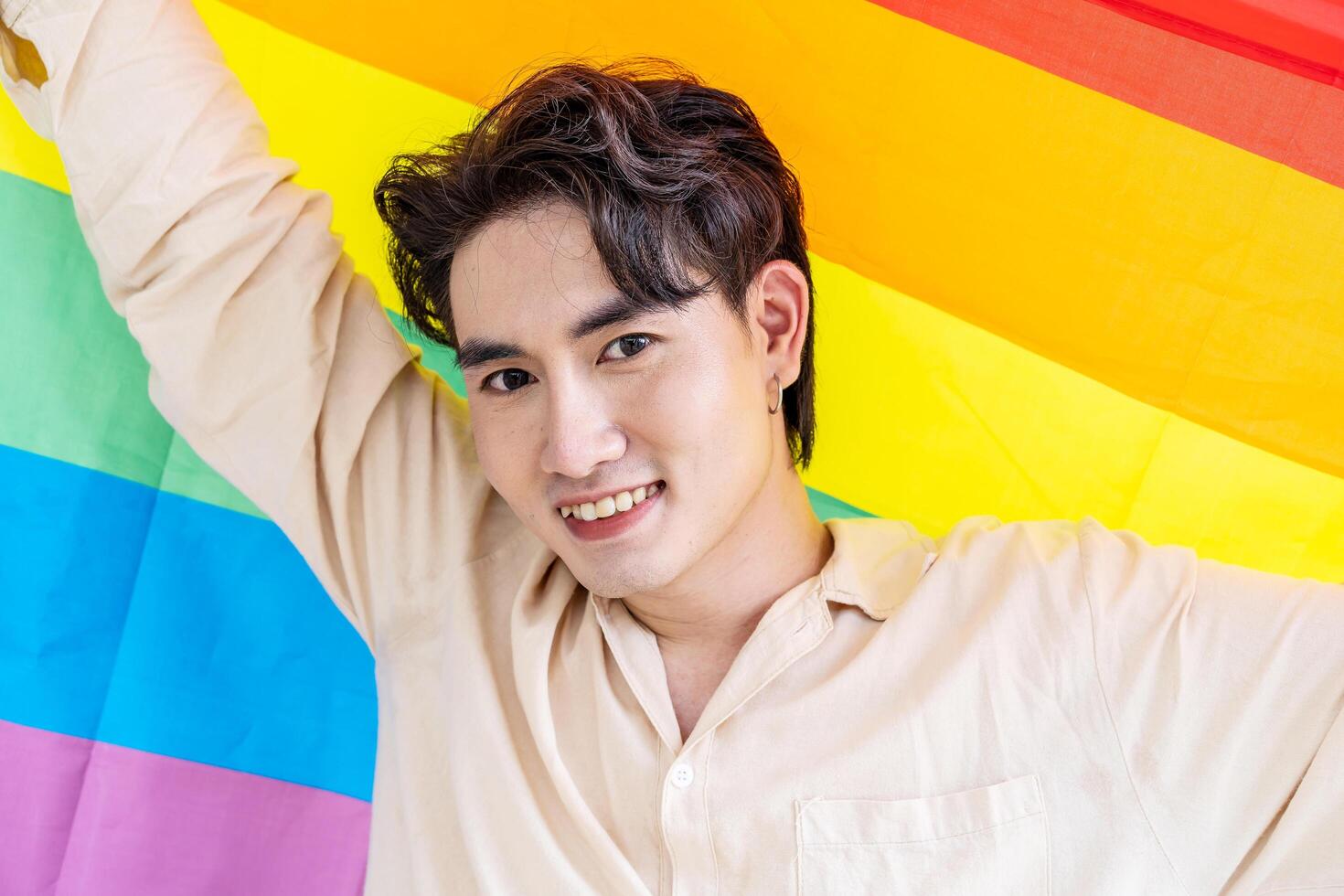 Portrait of transgender or gay man smiling in front of camera with pride rainbow flag isolated on white background with copy space. People lifestyle fashion lgbtq concept photo